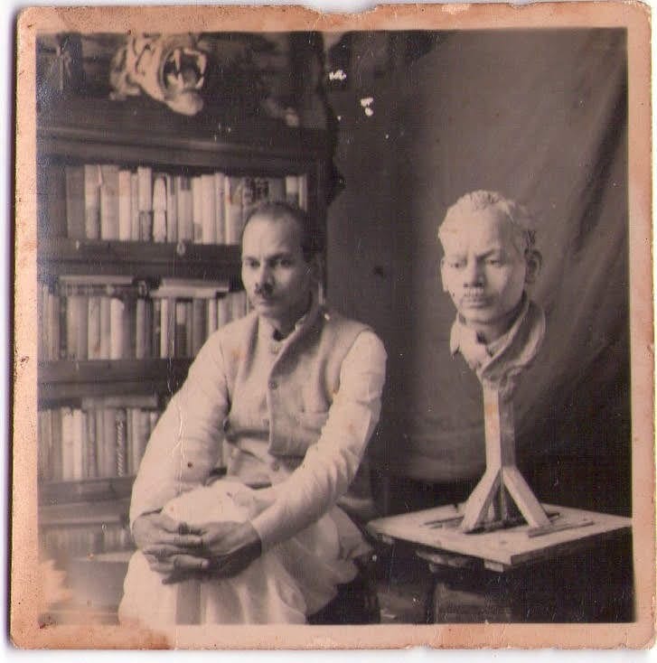 The artist in his studio beside a clay bust